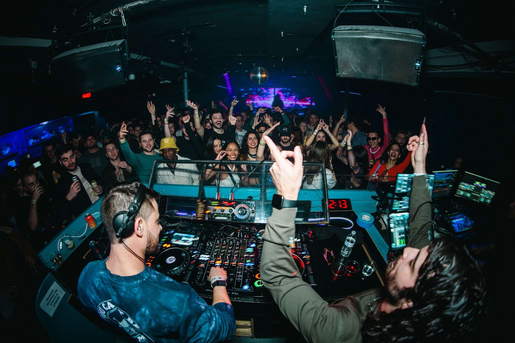 two djs at a dj booth in front of a crowd