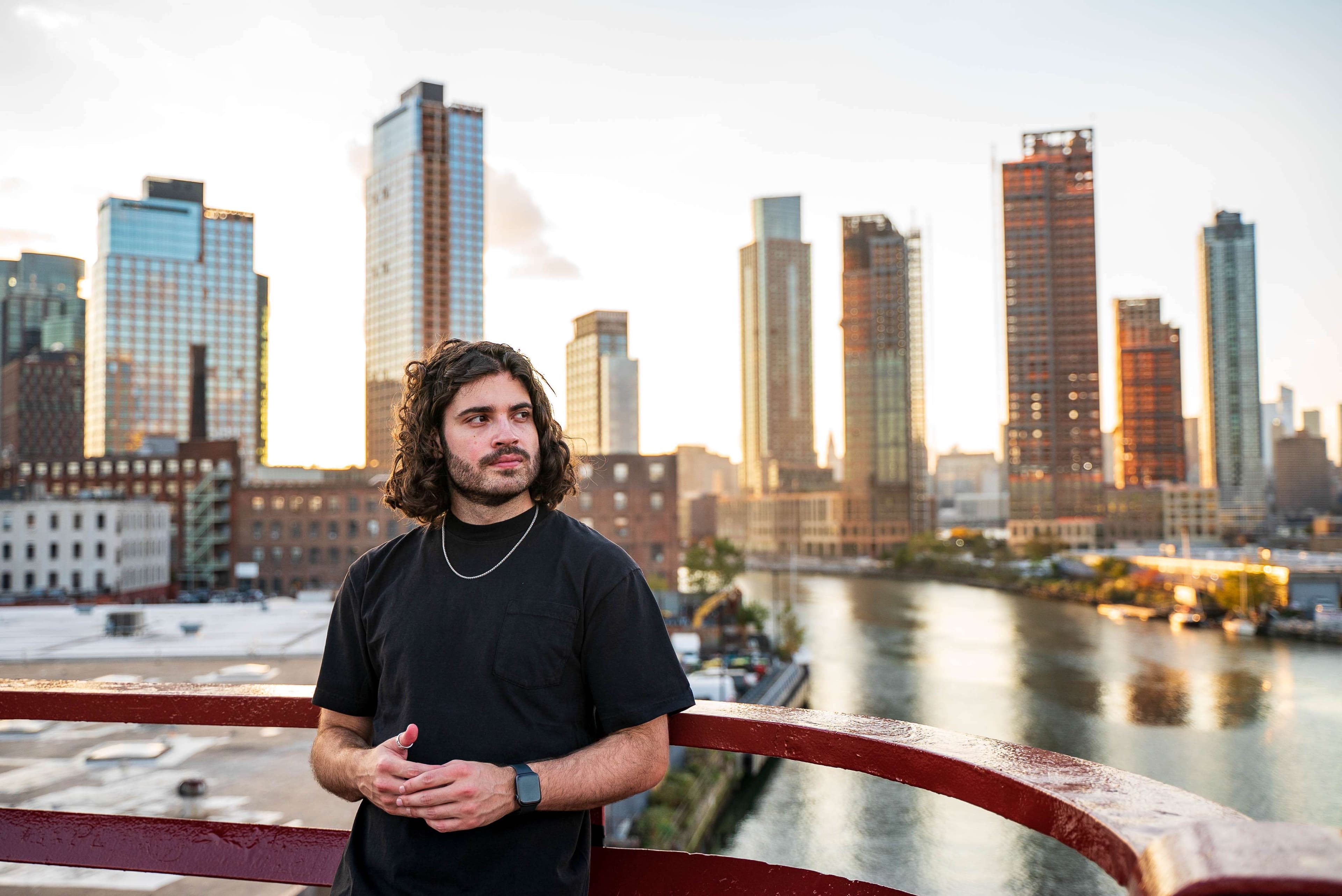 a man standing on a bridge with a city in the background